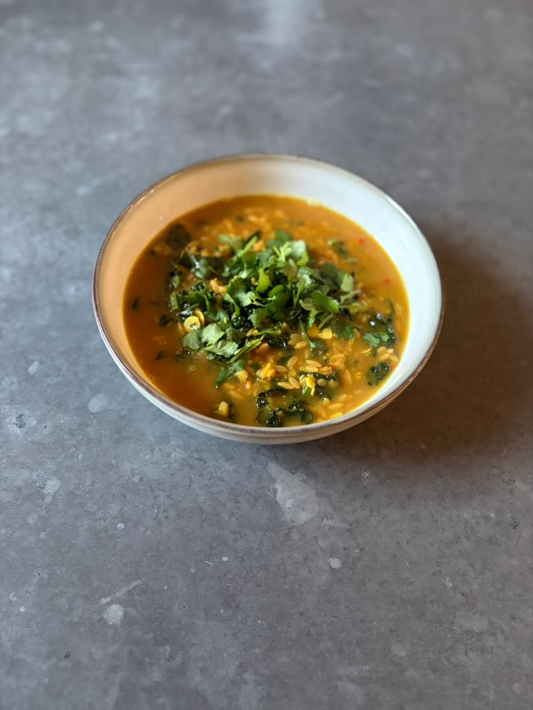 High protein coconut ginger soup with red lentils and greens in a bowl, healthy high fibre meal